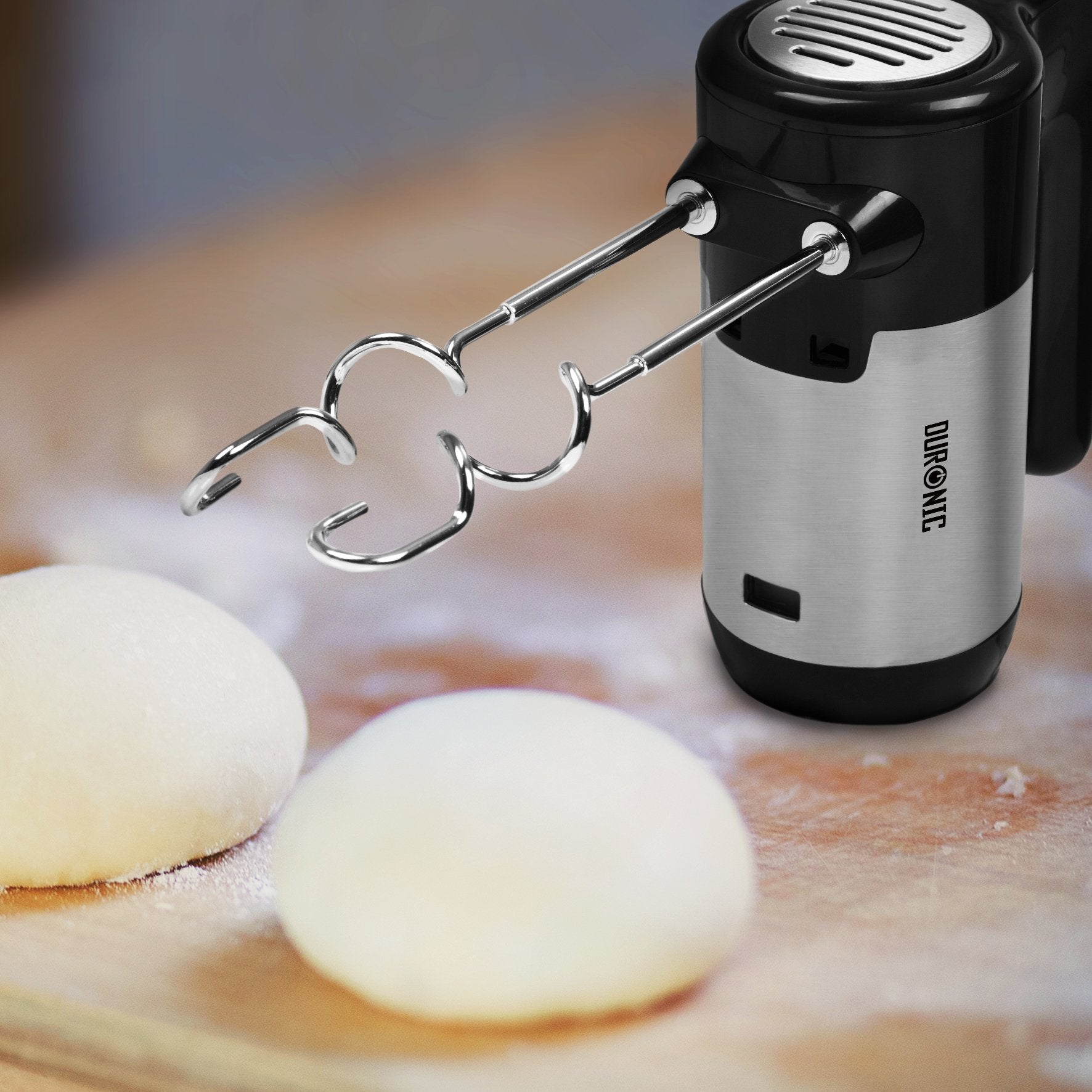 Duronic HM3 Batidora Amasadora Eléctrica Mostrando la batidora con los ganchos amasadores insertados, colocada junto a masas de panadería preparadas sobre una tabla de madera