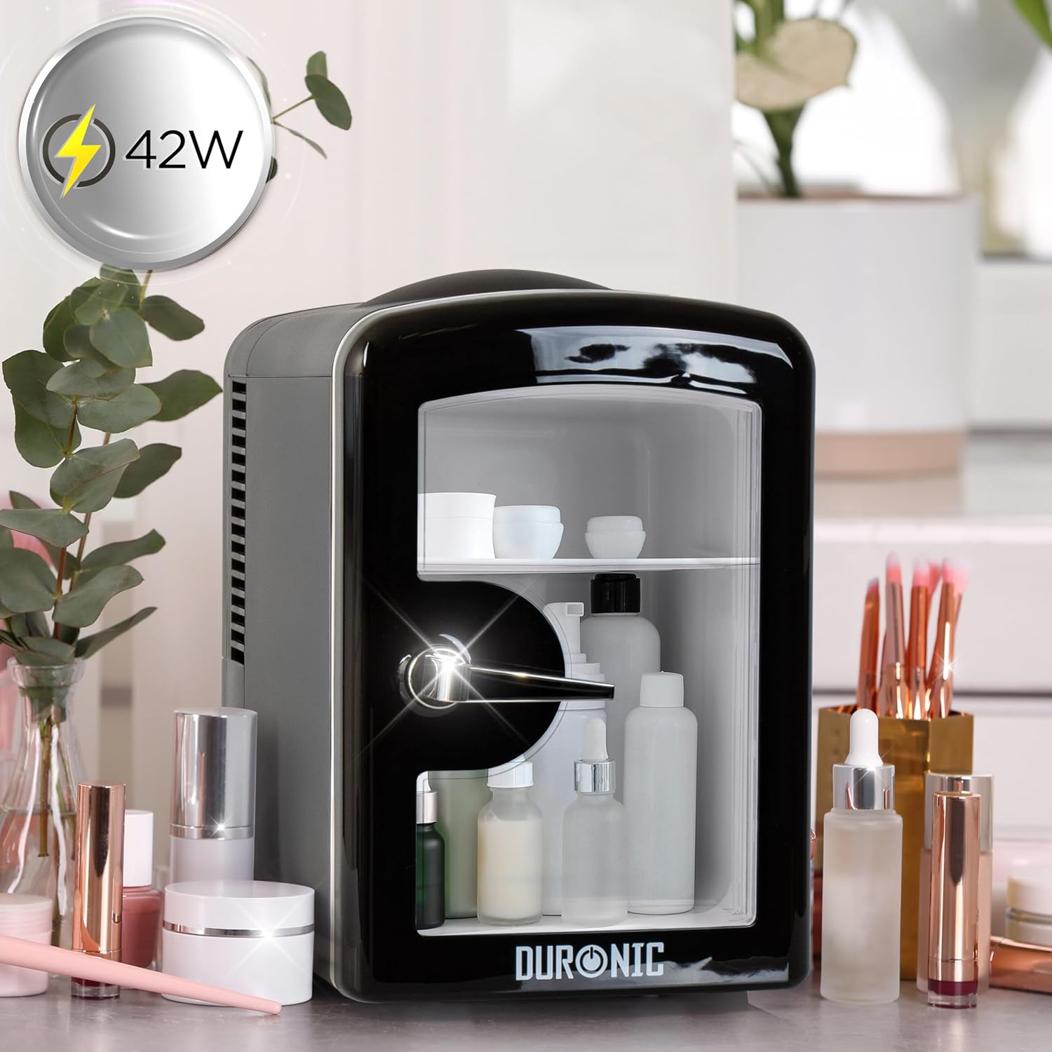 Duronic MFW4 BK Mini Nevera 4L 42W Frigorífico Portátil Mostrando la mini nevera en un entorno de tocador o cuidado personal, organizada con diversos productos de cosmética y cuidado de la piel en su interior y alrededor, destacando su potencia de 42 W en una burbuja informativa superior