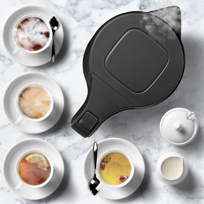 Duronic EK17 BK Hervidor de Agua Eléctrico 2200 W, 1,7 L, Compacto sin BPA | Mostrando una vista cenital del hervidor eléctrico negro en funcionamiento, rodeado por tazas de té, café y otras infusiones servidas sobre una superficie de mármol