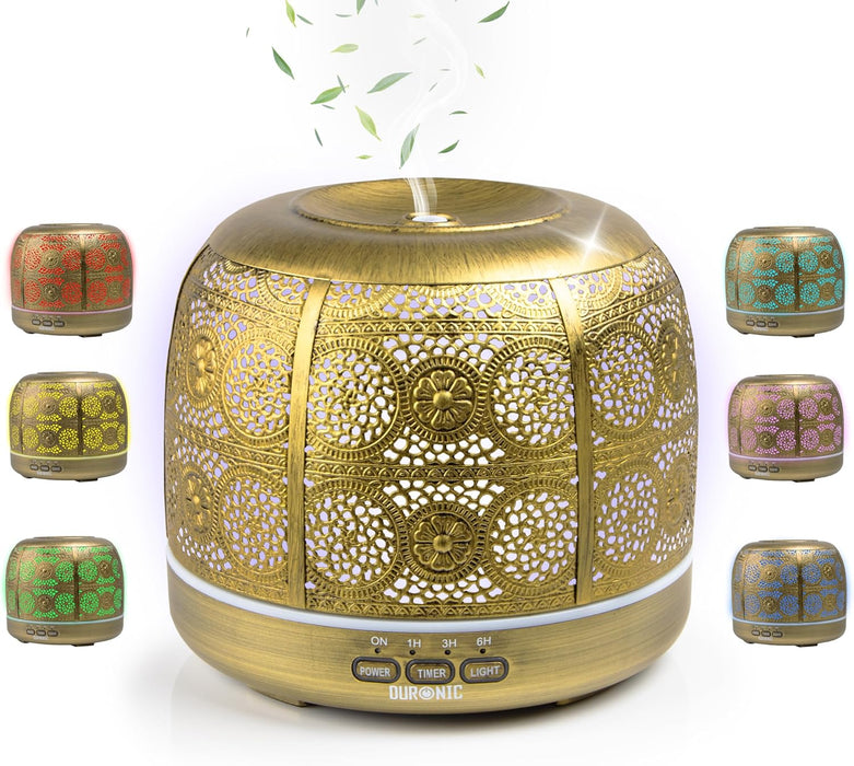 Duronic AD43 Difusor de Aromas y Brumizador de Aceites Esenciales Mostrando el difusor de aromaterapia de 500 ml en color dorado con carcasa metálica calada, expulsando bruma por la parte superior y rodeado de muestras de su iluminación LED ambiental en tonos rojo, amarillo, verde, turquesa, morado y azul, con los botones de control frontal POWER, TIMER y LIGHT.
