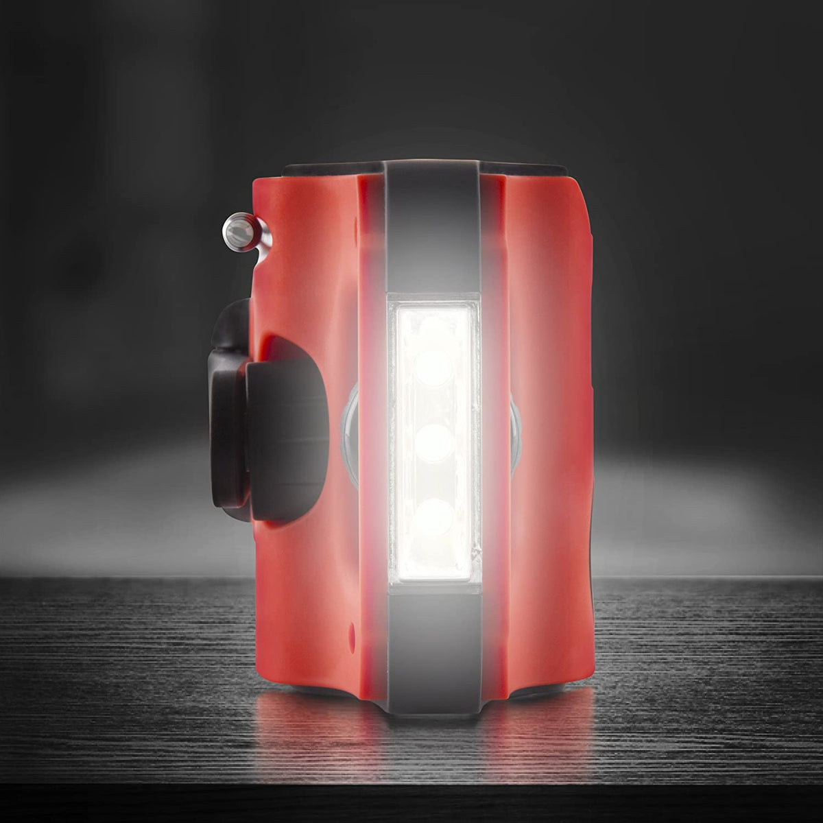 Duronic Apex Radio Solar de Emergencia con Manivela y Batería Recargable | Mostrando un primer plano lateral de la radio portátil de emergencia sobre una superficie oscura, con la lámpara LED de lectura integrada encendida y emitiendo una luz brillante e intensa
