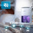 Duronic DH07 WE, deshumidificador eléctrico portátil, con el depósito iluminado en morado colocado en una mesita de noche junto a una persona durmiendo, indicando su funcionamiento silencioso de 43 dB