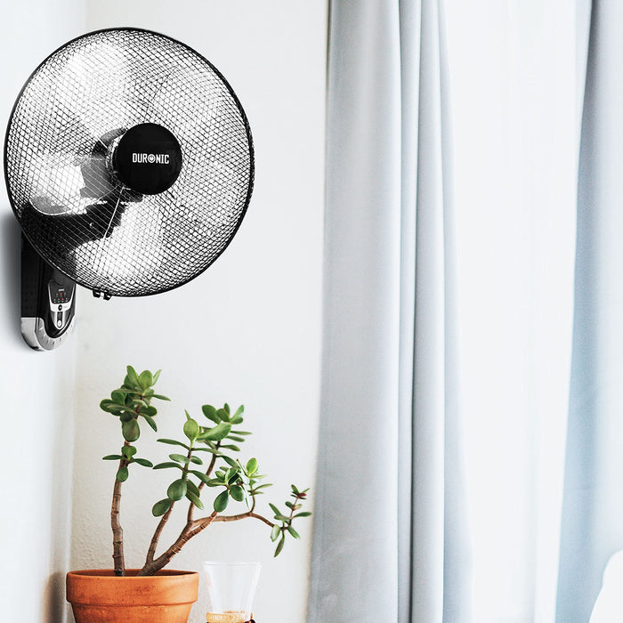 Duronic FN55 Ventilador de pared Mostrando el ventilador de pared instalado en una habitación luminosa junto a una planta verde en una maceta