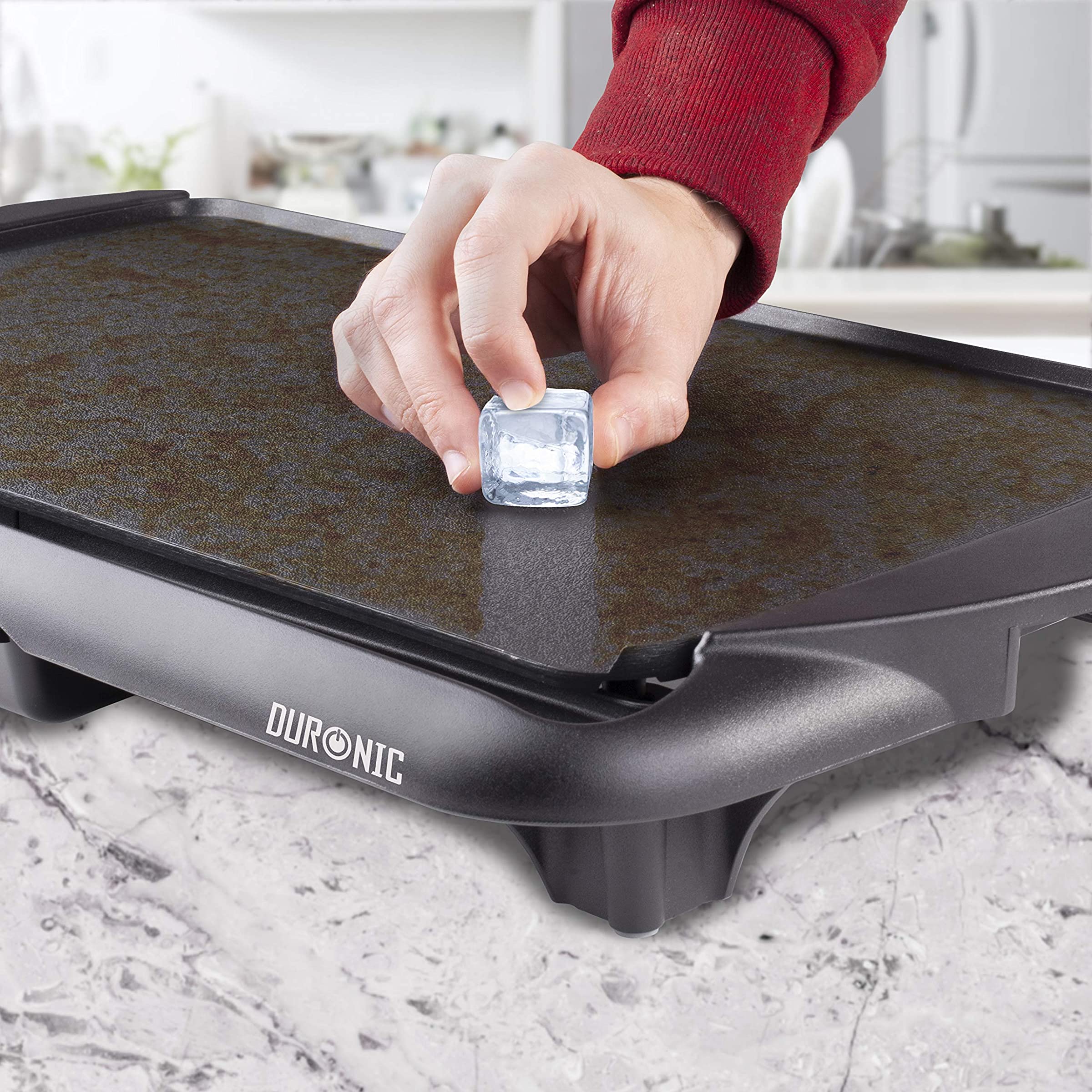 Duronic GP20 Plancha Eléctrica Grill Mostrando la superficie antiadherente de la plancha, donde un hielo se coloca sobre ella para ilustrar sus propiedades térmicas y de calidad de construcción
