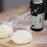 Duronic HM3 Batidora Amasadora Eléctrica Mostrando la batidora con los ganchos amasadores insertados, colocada junto a masas de panadería preparadas sobre una tabla de madera