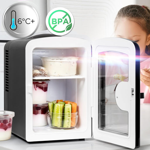 Duronic MFW4 BK Mini Nevera 4L 42W Frigorífico Portátil Mostrando la mini nevera con la puerta abierta y su interior organizado con recipientes de alimentos, yogures y vegetales, destacando en la parte superior sellos informativos de temperatura de 6°C+ y certificación libre de BPA, mientras una persona se encuentra al fondo