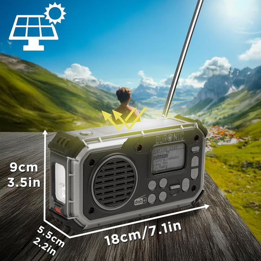 Duronic SDAB1 Radio Solar, Radio Emergencia Solar Dinamo, Radio Dinamo Mostrando las dimensiones de la radio de emergencia (18 cm de largo, 9 cm de alto y 5.5 cm de profundidad) sobre una superficie de madera con un paisaje montañoso de fondo